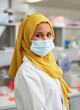 © Trevor Adeline/Caia Image - Portrait confident female scientist in hijab and face mask in laboratory