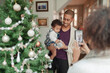 © Paul Bradbury/Caia Image - Woman photographing husband and baby daughter at Christmas tree