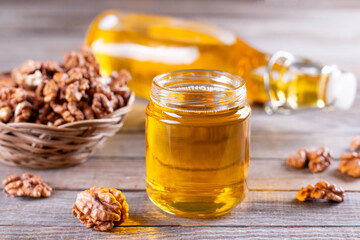 Wall Mural - Walnut oil in a small jar and kernels on old wooden background in rustic style