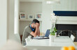 © Paul Bradbury/Caia Image - Tired man with head in hands working from home at laptop