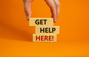 get help here symbol. male hand builds stack from blocks with words 'get help here'. beautiful orang