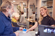 © Monkey Business - Senior Man Making Contactless Payment To Stylist In Salon With Credit Card