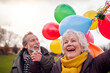 © Monkey Business - Loving Senior Couple Holding Balloons Enjoying Autumn Or Winter Walk Through Park Together