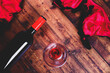 Flat lay of a ladies red bra and knickers with a bottle of red wine and wine glass on a wooden floorboard background with a matt filter applied
