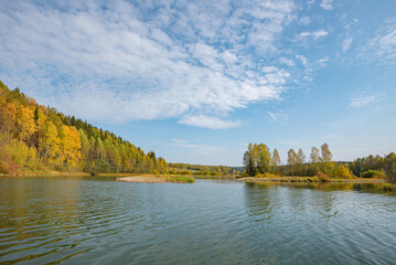 Wall Mural - autumn forest trees are reflected in the river water of the panoramic landscape. blue sky with cloud