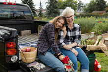 Portrait Of Mother And Daughter Sitting On Rear Of Pickup Truck