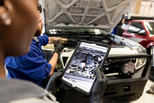 Auto Mechanics With Digital Tablet Modifying SUV Engine In Garage