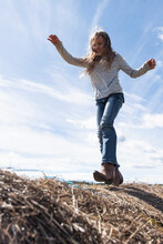 Happy Girl In Cowboy Boots Playing On Sunny Farm Hay Bales