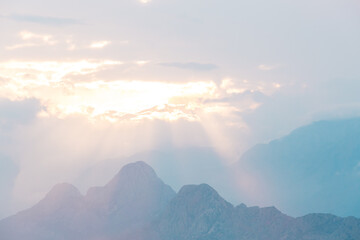 Wall Mural - Sunset in the mountains, the sunbeams break through the clouds and illuminate the mountain.