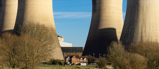 Farmhouse looking small between cooling towers