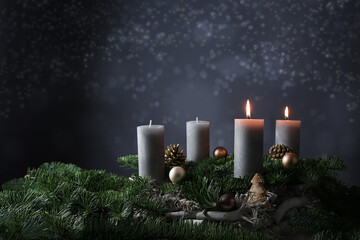 Second advent with two burning candles on fir branches with Christmas decoration against a dark grey background, copy space