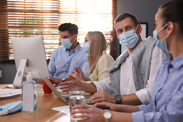 Wall Mural - Coworkers with masks in office. Protective measure during COVID-19 pandemic