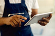 © Drazen - Close-up of mechanic working on digital tablet in auto repair shop.