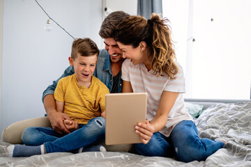 Wall Mural - Happy family spending time at home and looking something fanny on tablet.