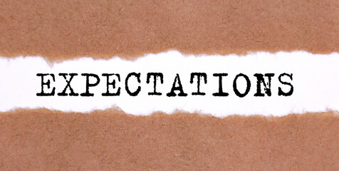 Poster - The text EXPECTATIONS appearing behind torn brown paper.