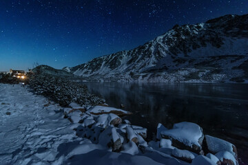 Wall Mural - Starry sky in winter Polish Tatras near a mountain lake covered with ice	