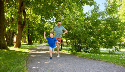 Wall Mural - family, fatherhood and people concept - happy father with little son compete in running at summer park