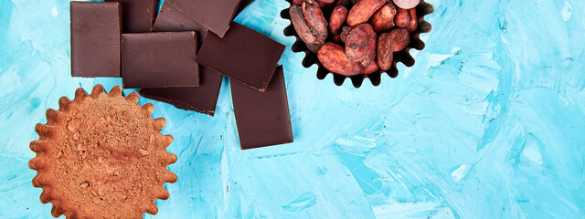 Wall Mural - Banner of Cocoa beans background on blue table. Dark chocolate pieces