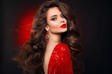 Beautiful Sexy Brunette In Red Dress With Healthy Curly Hair And Glamour Makeup. Fashion Beauty Girl Isolated On Black Studio Background.