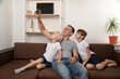 © somemeans - Father and two sons take a selfie while sitting on the couch. Leisure with children