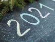 © Alyona Shu - New year 2021 written in colored chalk on a blackboard dark for chalk. Spruce branches. Garland lights.