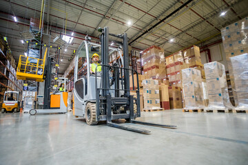 Forklift operator during work in large warehouse