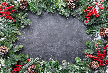 Wall Mural - christmas and new year background with fir branches and snowfall on dark stony board