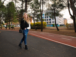  Young cheerful fitness woman walking in a garden area of the city