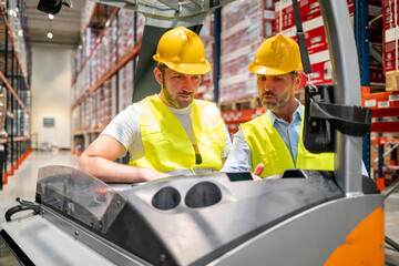 Warehouse worker learns how to use forklift with instructor