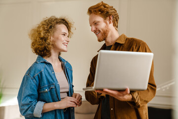 Attractive young couple using laptop while standing