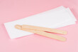 © YuliiaMazurkevych - Wax strips for epilation and wooden sticks on pink background