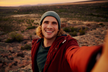 Portrait of happy and smiling hiker taking a selfie on the top of the mountain