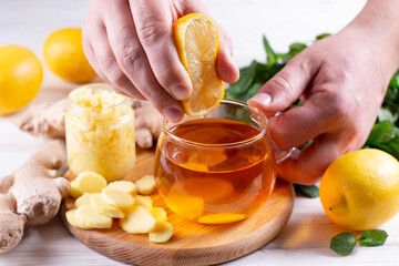 Poster - Man squeezing lemon into tea with mint in cup. Fall immune system booster