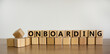 Onboarding symbol. 'Onboarding' written on wooden blocks. Business and onboarding concept. Beautiful wooden table, white background. Copy space.