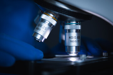 Wall Mural - close-up shot of sample slide and microscope with metal lens at laboratory.