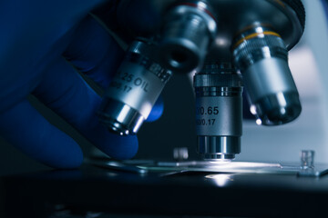 Wall Mural - close-up shot of sample slide and microscope with metal lens at laboratory.