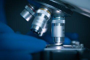Wall Mural - close-up shot of sample slide and microscope with metal lens at laboratory.