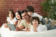 © Friends Stock - Family time. Joyful latin family with cute little kids spending time together at home. Loving father watching cartoons together with children, lying on the bed