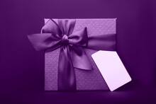 A Purple Gift Box With A Tag On The Black Background.