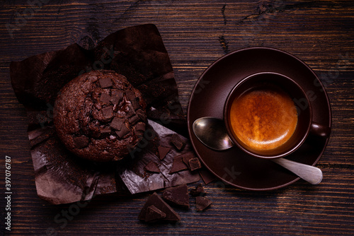 Fotografia on the dark wooden table, with top view, a chocolate muffin and a cup of creamy espresso