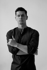 Black and white background. Closeup portrait of handsome fit brunette young man in black t shirt.