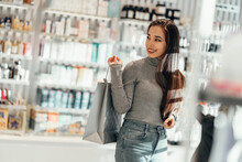 Beautiful Smiling Asian Girl Chooses Buys Cosmetics In The Store. Shopping