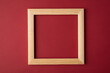 Photo of blank wooden frame isolated on burgundy background