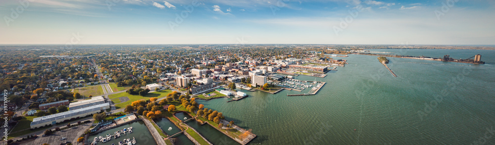 Incredible aerial city skyline panorama photograph of Sandusky, Ohio from the shoreline of the bay in Lake Erie with parks and harbors seen below on a sunny day. - obrazy, fototapety, plakaty 