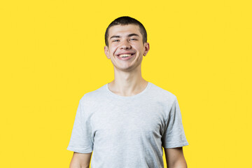 happy smiling caucasian 20 years old man over yellow background. casual clothes. copy space. studio shot