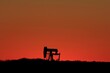 oil pump at sunset with a red sky south of Sterling Kansas USA out in the country.
