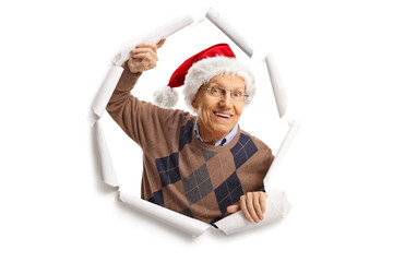 Canvas Print - Elderly man breaking through paper and wearing a christmas santa claus hat