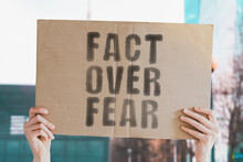 The Phrase " Fact Over Fear " On A Banner In Men's Hand With Blurred Background. Truth. True. Realist. Reality. Stress. Reality. Fake. Untruth. Liar
