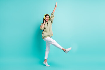 Sticker - Full length photo portrait of cool woman wearing green headphones dancing standing on one leg isolated on vivid turquoise colored background