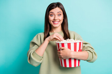 Poster - Photo portrait of immersed excited woman holding large popcorn bucket eating isolated on vivid turquoise colored background